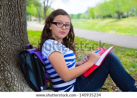 Clever student teenager girl with school bag resting relaxed under park tree