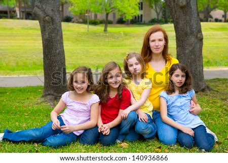 Mother teacher with daughter pupils in playground park group portrait on lawn
