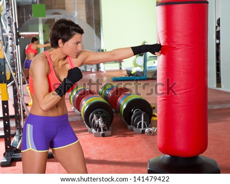 Crossfit fitness woman boxing with red punching bag at gym