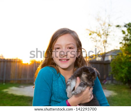 Children kid girl playing with puppy dog hairy chihuahua in backyard sunset