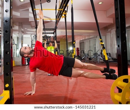 Crossfit fitness TRX training exercises at gym woman and man side push-up workout