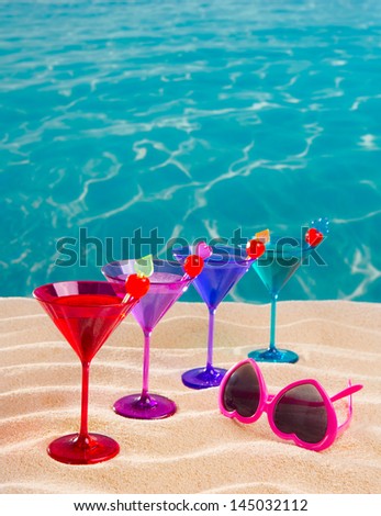 colorful cocktail in a row with cherry on tropical sand beach of turquoise sea