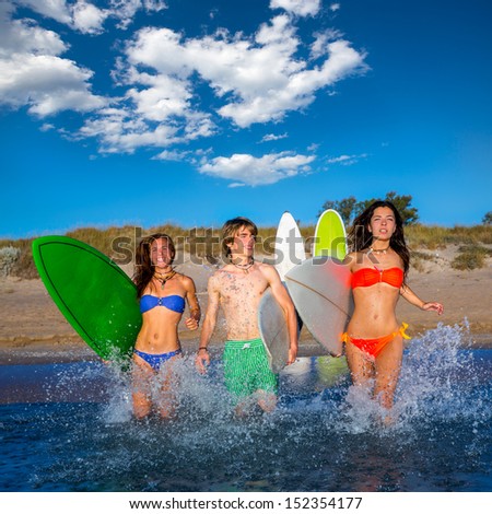 surfer teenagers boys and girls group running happy to the beach splashing water