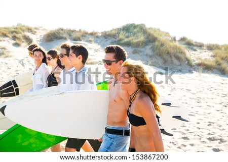 Surfer teen boys and girls group walking on beach sand