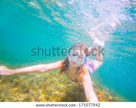 snorkeling blond kid girl underwater with goggles and swimsuit in Mediterranean sea