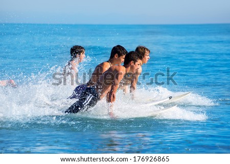 Boys teen surfers surfing running jumping on surfboards at the beach
