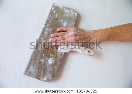 Plastering man hand with plaste and plaster spatula trowel in wall