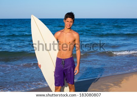Boy teen surfer happy holing surfboard on the beach shore