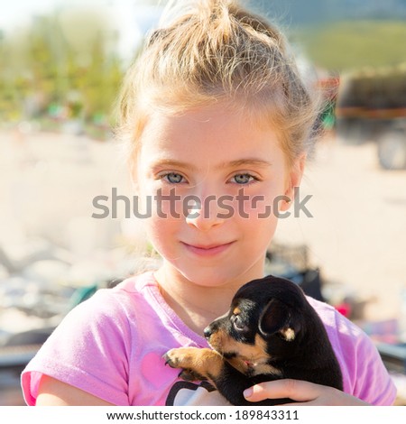 Blond kid girl playing with puppy dog smiling with blue eyes