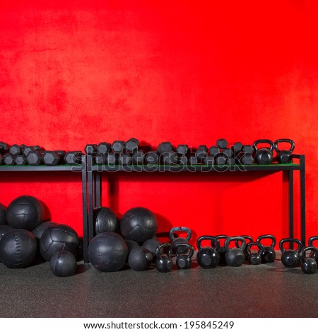 Kettlebells dumbbells and weighted slam balls weight training equipment at gym red wall