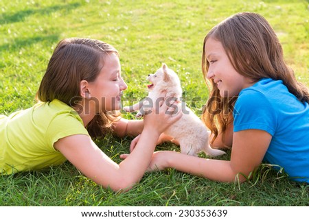 twin sister kid girls and puppy dog happy playing with pet lying in backyard lawn