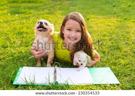 kid girl and puppy dog doing homework with chihuahua pets lying in backyard lawn