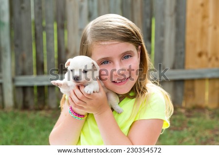 Blond kid girl with puppy pet chihuahua playing happy with doggy outdoor