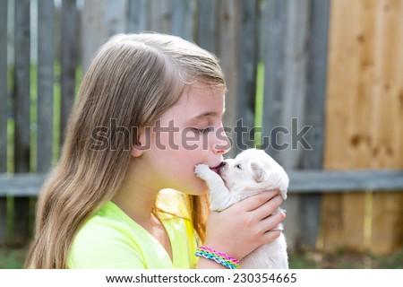Blond kid girl kissing puppy pet chihuahua playing happy with doggy outdoor