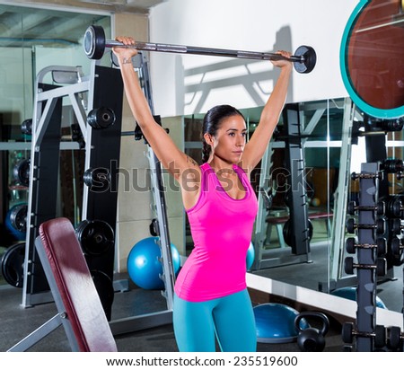 brunette girl wide grip barbell shoulder press workout at gym