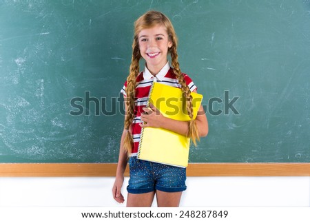 Blond braids schoolgirl with student spiral notebook at class green chalk board