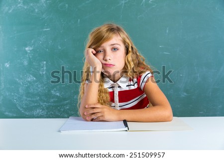 Boring sad expression student schoolgirl on classroom desk at school green chalk board