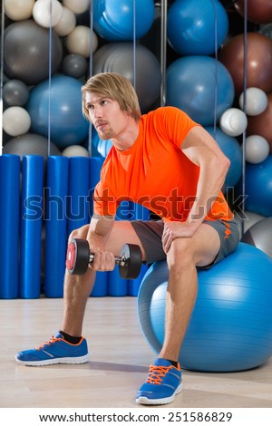 dumbbell concentrated biceps curl  man workout at gym sit on swiss ball fitball