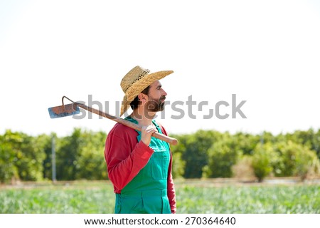 Farmer man with hoe looking at his orchard field with hat