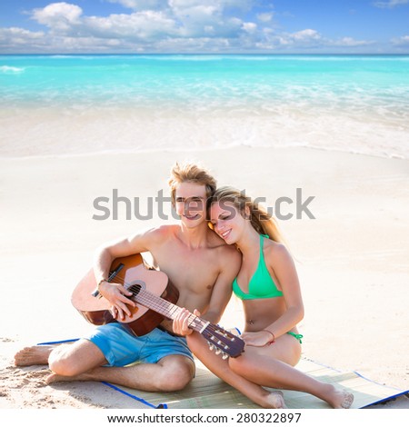 Blond young tourist couple playing guitar at beach