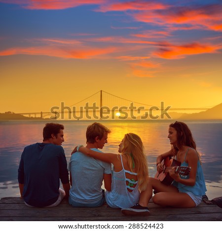 Friends group playing guitar in sunset pier at dusk in San francisco photo mount