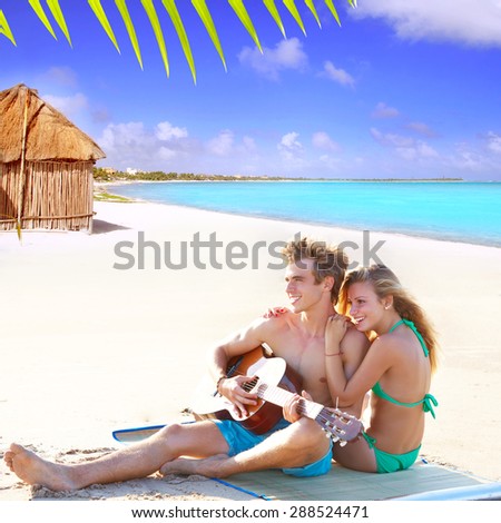 Blond couple sitting in the Cancun beach sand playing guitar photo mount