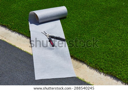 Artificial grass turf installation in garden with tools and joint roll