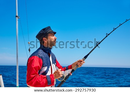 Beard sailor man fishing rod trolling in saltwater in a boat trolling with captain cap