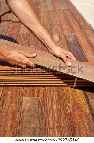 Ipe decking installation with carpenter hands holding tropical wood slats