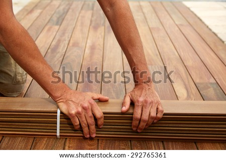 Ipe decking installation with carpenter hands holding tropical wood slats