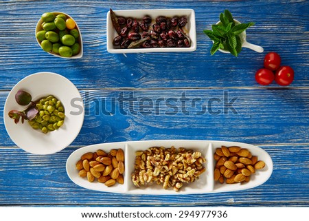 Mediterranean tapas black olives capers and nuts on blue wood table