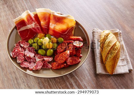 Tapas of Spain with ham bread olives sausage and chorizo on wooden background
