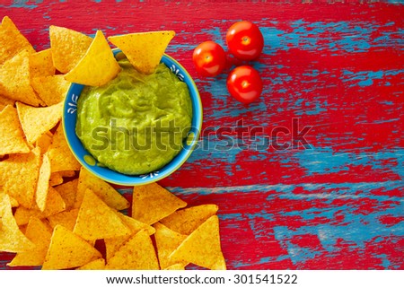 Mexican food nachos and guacamole in red grunge background