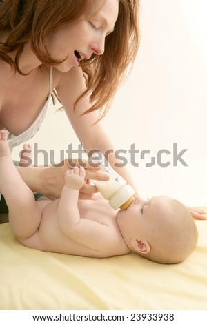 stock photo Redhead mother giving milk on bottle to her nude baby 
