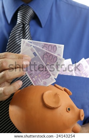businessman insert euro notes in clay piggy bank