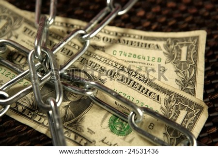One Dollar notes in chains studio shot over brown background