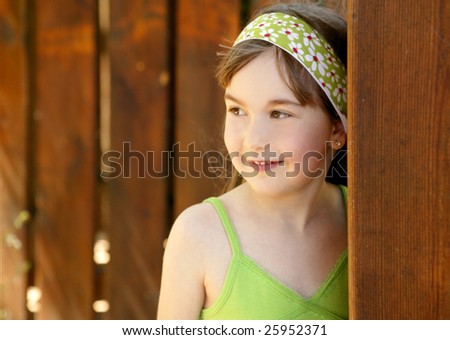 beautiful young girl portrait playing hidden behind the wooden door