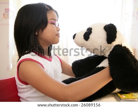 Asian girl looking at her panda teddy bear