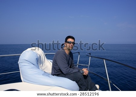 Man on bow boat relaxed on bean bag over blue sea