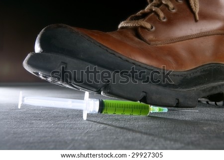 Boot treading a green liquid syringe, leaving drug addiction metaphor