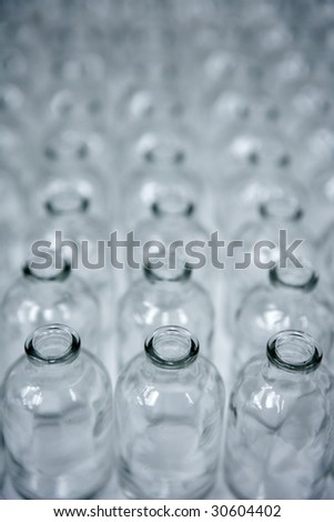 Glass transparent empty bottles in rows, cosmetics assembly line