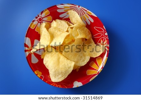 Potato fried chips on red plate over blue background