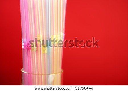Colorful plastic drink straw over red copy space background