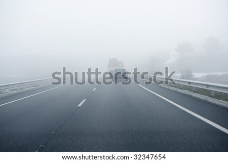 Foggy gray road, cars driving fading into the fog