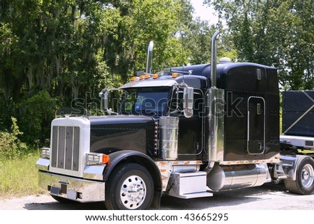 Black huge lorry american truck with stainless steel in green outdoor