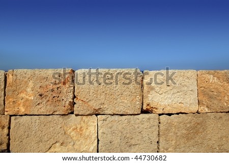Big stone bricks masonry wall on port dock under blue sky