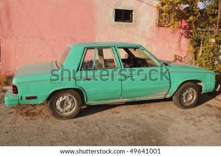aged old vintage green car in pink wall Cancun Mexico