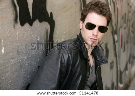 rocker rock star young man sunglasses on silver wall city outdoor