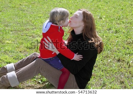 mother and daughter kissing mouth lips hug in winter meadow grass