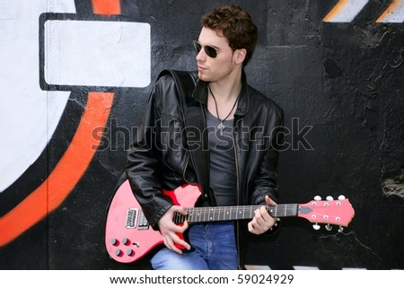 rocker rock star man on black graffiti holding red electric guitar leather jacket
